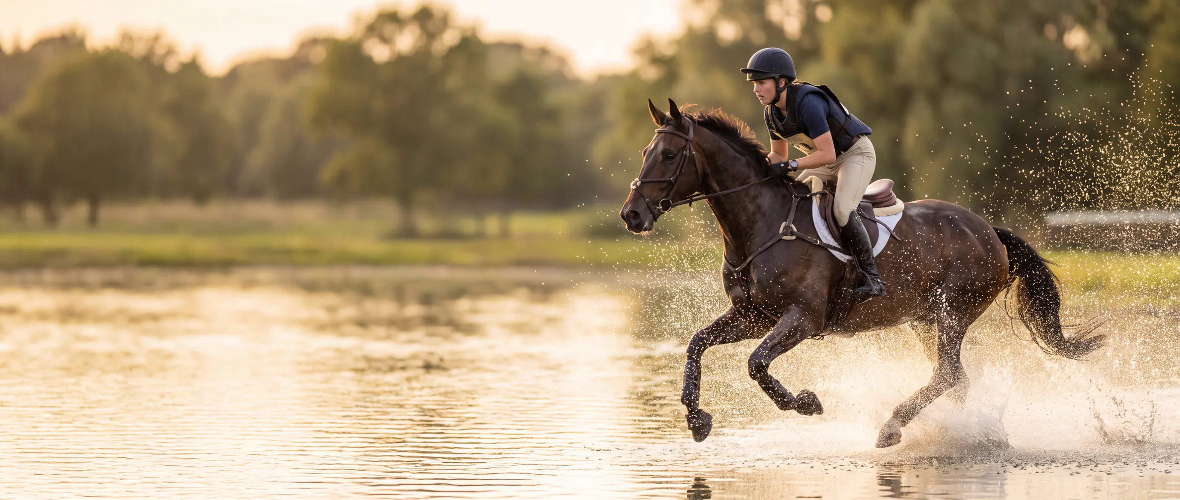 Rider and sport horse galloping through water on a cross-country course